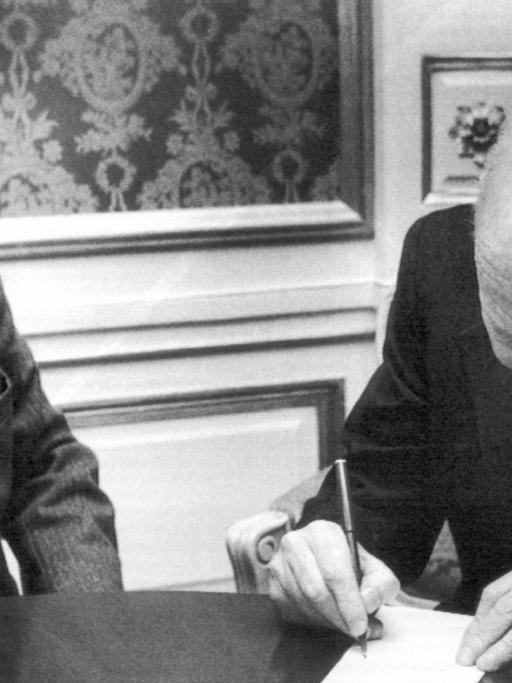 Der Vizevorsitzende der schwedischen Bank (Svenska Handelsbanken), Tore Browald (l), beobachtet den Literatur-Nobelpreisträger Isaac Bashevis Singer (r, "Mein Vater der Rabbi") beim Unterschreiben des Nobelpreis-Schecks am 11. Dezember 1978 in Stockholm.