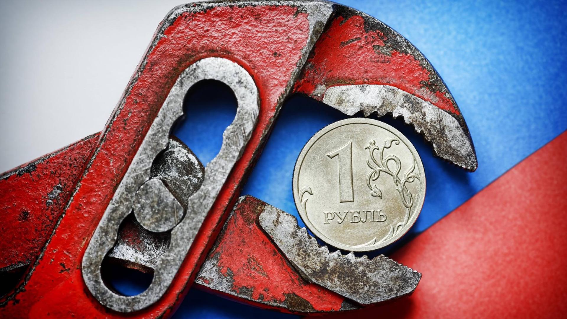 Eine Ein-Rubel-Münze vor russischer Fahne in der Zange Eine Ein-Rubel-Münze vor russischer Fahne in der Zange