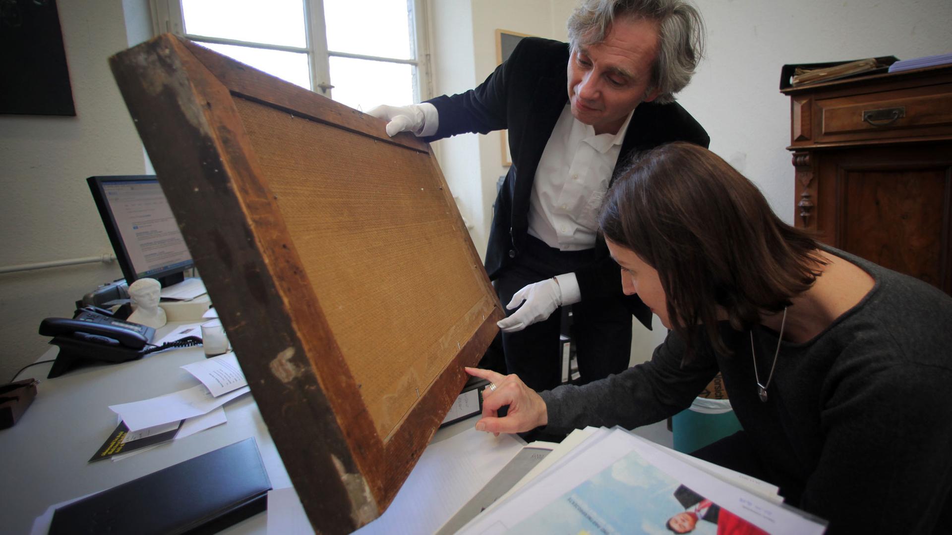 Die Experten für Provenzienzforschung im Museum Wiesbaden, Miriam Merz und Peter Forster, untersuchen am 10.12.2013 im Landesmuseum Wiesbaden (Hessen) die Rückseite eines Bildes. Das Museum Wiesbaden hat 1999 begonnen, alle zwischen 1933 und 1945 erworbenen Kunstwerke auf ihre Herkunft zu überprüfen. Die Experten für Provenzienzforschung im Museum Wiesbaden, Miriam Merz und Peter Forster, untersuchen am 10.12.2013 im Landesmuseum Wiesbaden (Hessen) die Rückseite eines Bildes. Das Museum Wiesbaden hat 1999 begonnen, alle zwischen 1933 und 1945 erworbenen Kunstwerke auf ihre Herkunft zu überprüfen.