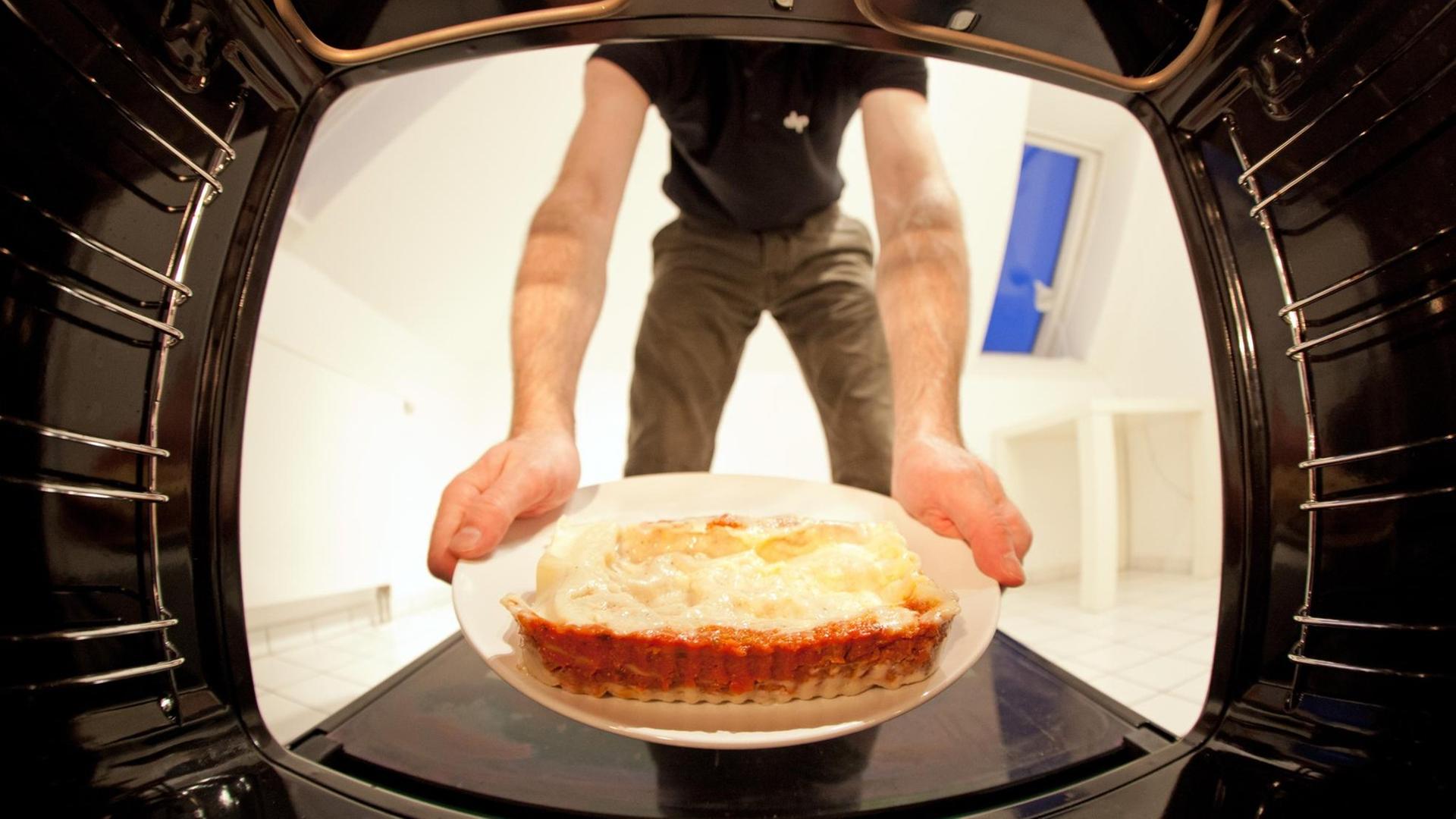 Eine Lasagne wird in den Ofen geschoben.