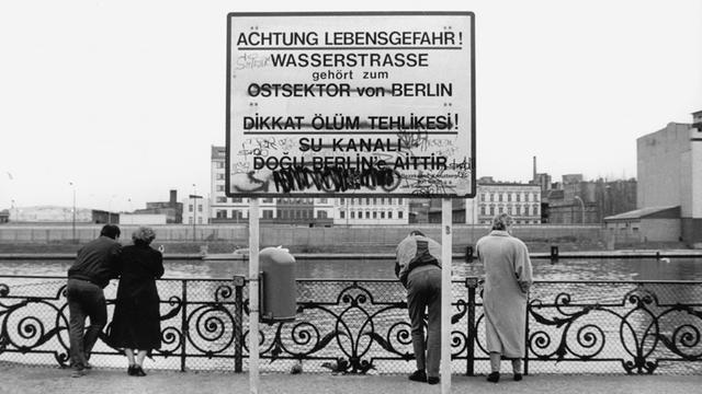 Die Spree im Jahr 1990 mit Blick auf den DDR-Teil der Stadt, ein Schild warnt vor jedem unbefugten Übertritt des Flusses.