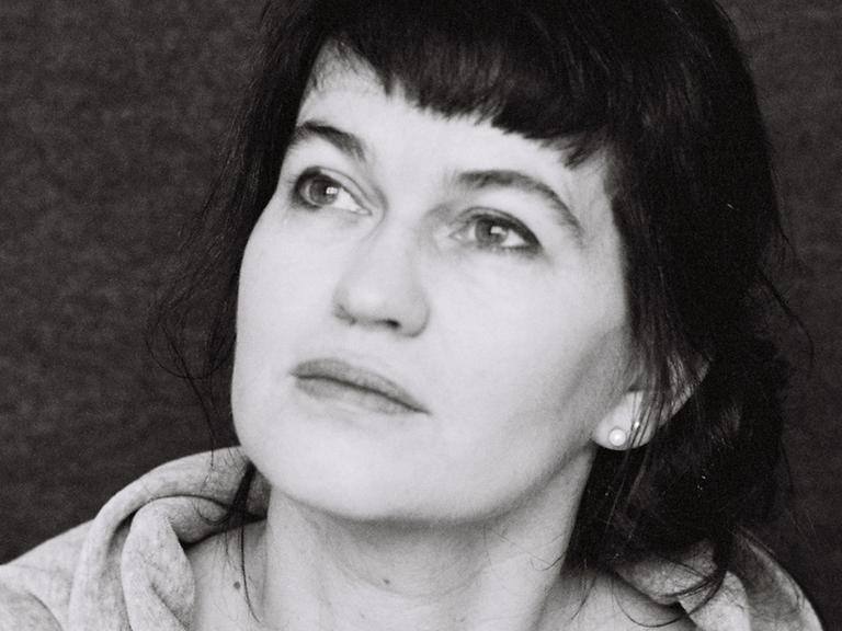 Eine schwarz-weiße Porträtaufnahme der Autorin Karin Kalisa. Sie blickt Richtung linker oberer Bildecke.