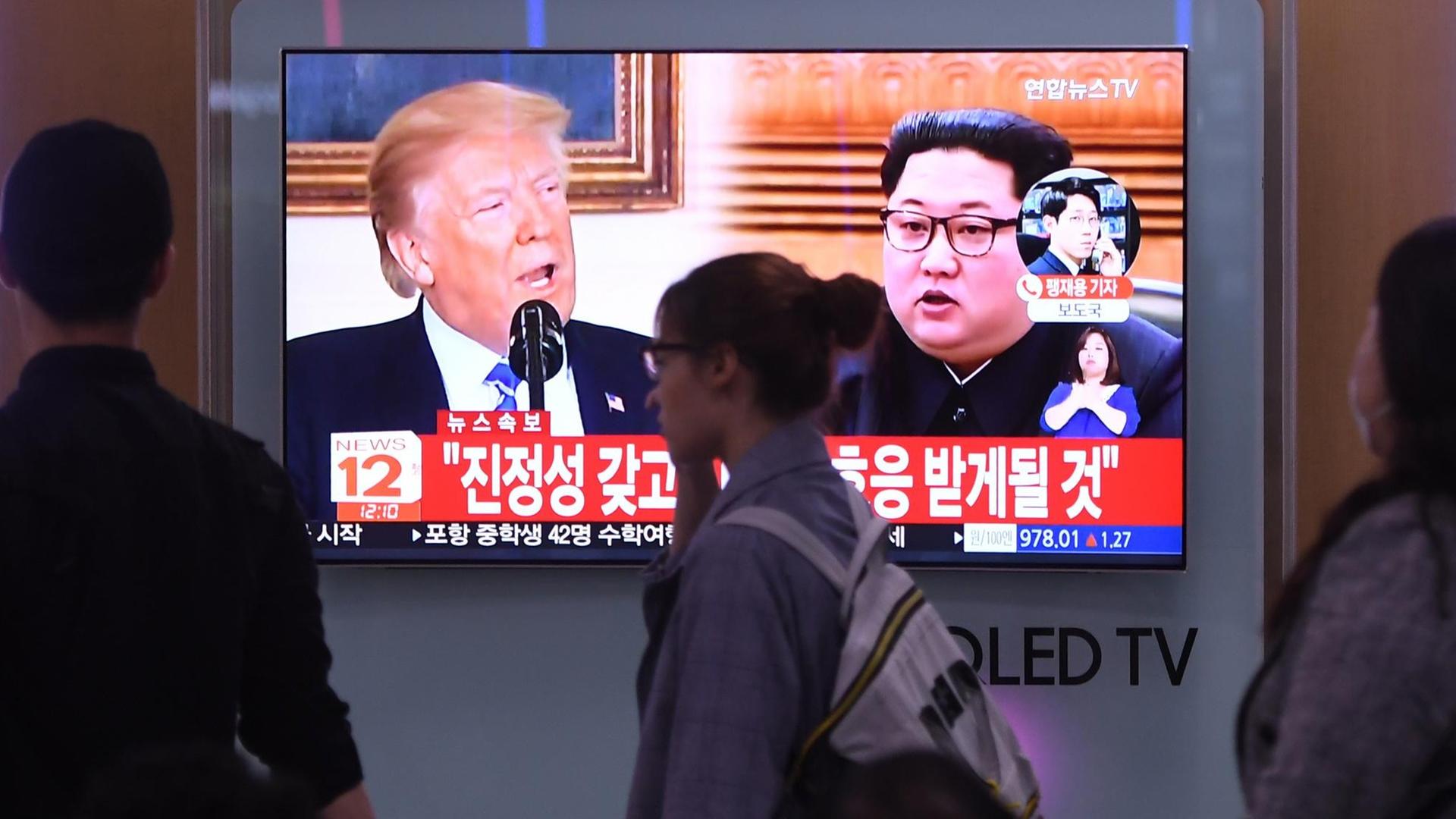 Menschen in Seoul laufen auf einem Bildschirm vorbei, auf dem US-Präsident Donald Trump und Nordkoreas Staatschef Kim Jong Un zu sehen sind. Menschen in Seoul laufen auf einem Bildschirm vorbei, auf dem US-Präsident Donald Trump und Nordkoreas Staatschef Kim Jong Un zu sehen sind.