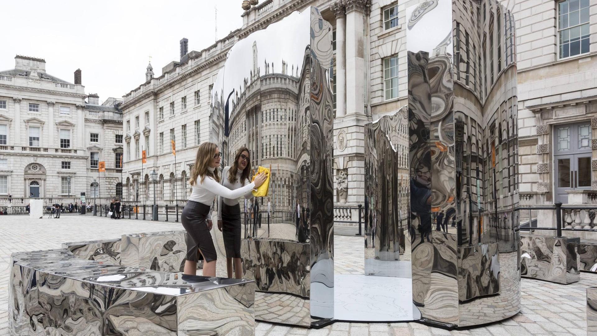 Vor dem Somerset House in London reinigt eine Angestellte eine Skulptur, die anlässlig der Design Biennale 2016 dort aufgestellt ist.