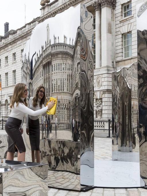 Vor dem Somerset House in London reinigt eine Angestellte eine Skulptur, die anlässlig der Design Biennale 2016 dort aufgestellt ist.