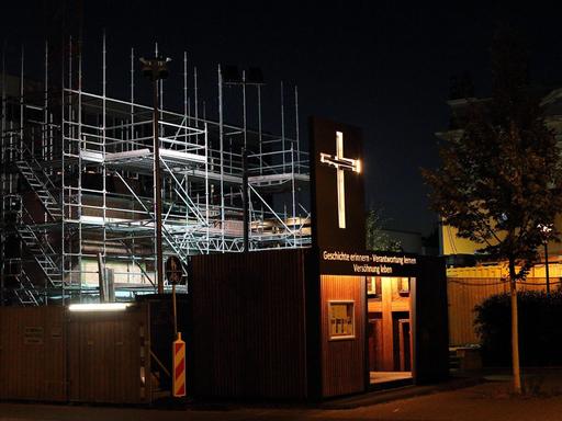 Ein künstlerisch gestalteter Container mit Nagelkreuz aus Coventry und der Aufschrift Geschichte erinnern - Verantwortung lernen - Versöhnung leben steht an der Baustelle für den Wiederaufbau des Turms der Garnisonkirche in Potsdam im Juli 2019.