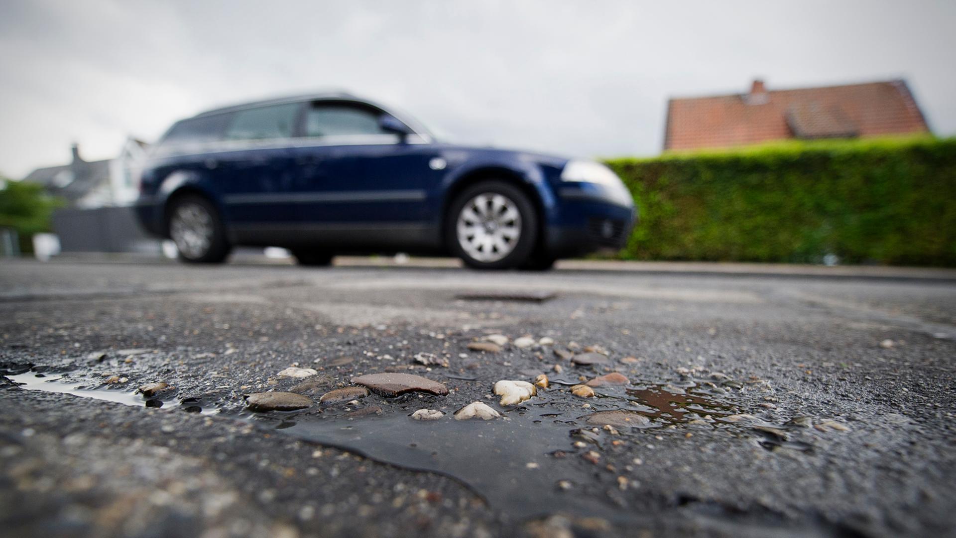 Ein Auto fährt am 19.08.2013 an einem geflicktem Schlagloch in einer Straße in Büderich (Nordrhein-Westfalen) vorbei. Ein Auto fährt am 19.08.2013 an einem geflicktem Schlagloch in einer Straße in Büderich (Nordrhein-Westfalen) vorbei.