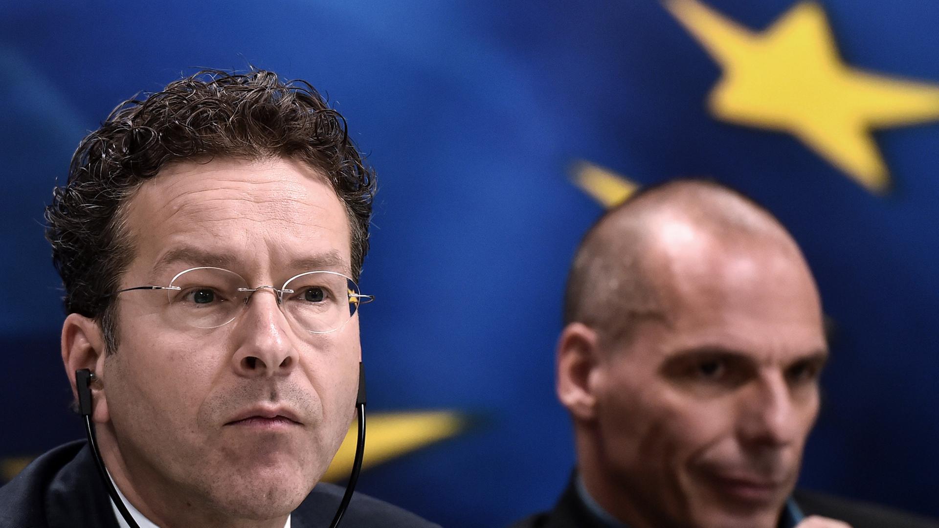 Eurogruppenchef Jeroen Dijsselbloem und der griechische Finanzminister Yanis Varoufakis bei einer Pressekonferenz in Athen. Dijsselbloen trägt einen Kopfhörer. Im Hintergrund ist die Europa-Fahne. Eurogruppenchef Jeroen Dijsselbloem und der griechische Finanzminister Yanis Varoufakis bei einer Pressekonferenz in Athen. Dijsselbloen trägt einen Kopfhörer. Im Hintergrund ist die Europa-Fahne.