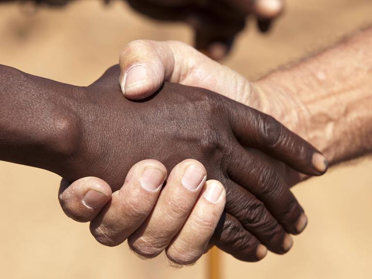 Ein Handschlag zwischen einem Schwarzen und Weißen.