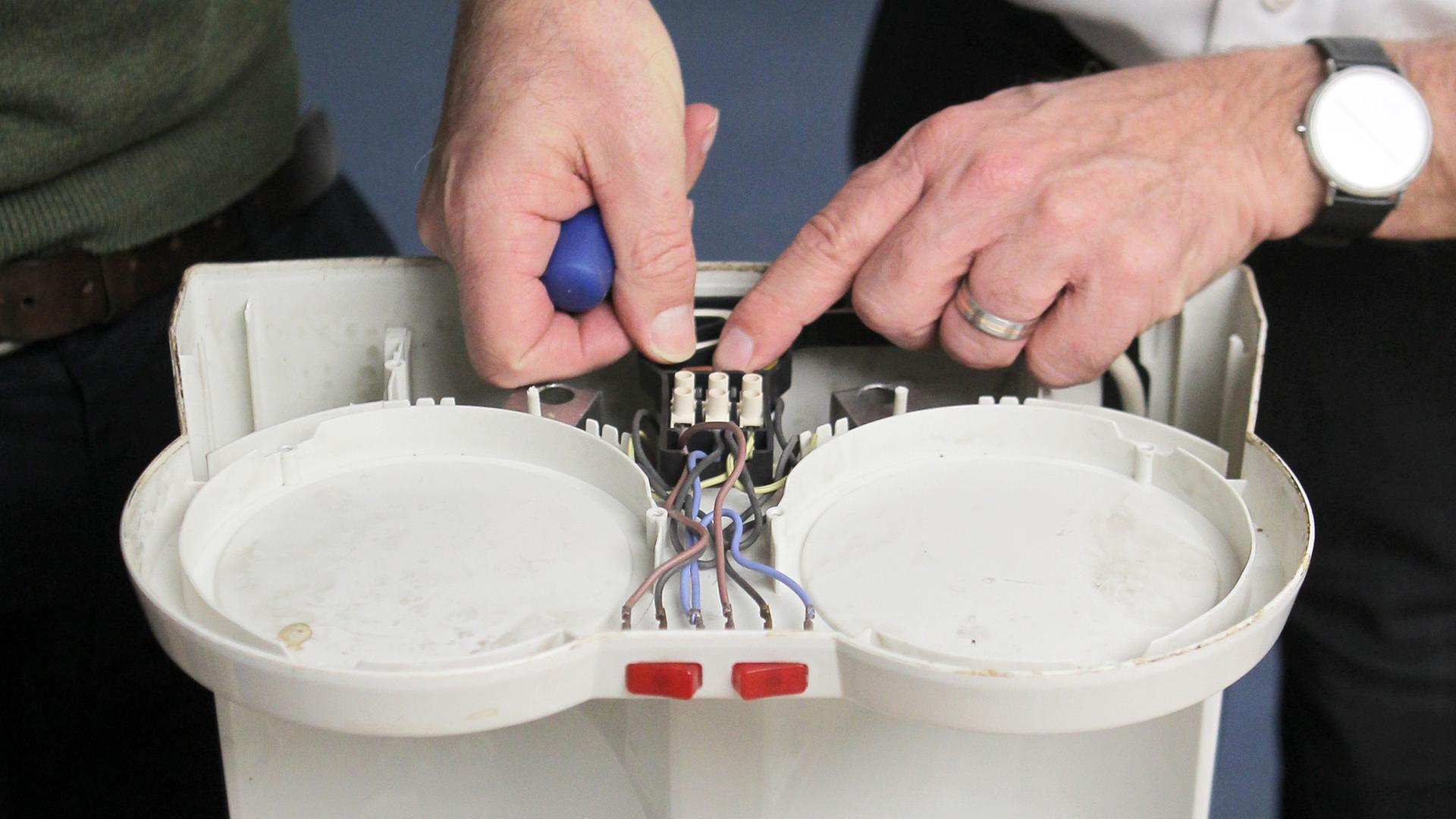 Zwei Hobby-Experten bei der Reparatur einer Kaffeemaschine Zwei Hobby-Experten bei der Reparatur einer Kaffeemaschine