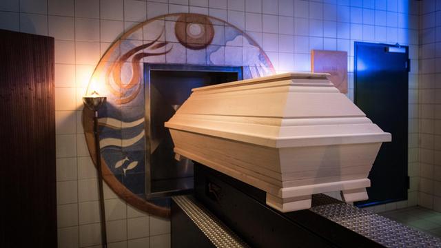 Ein Sarg wird in die Glut des Ofens im Krematorium geschoben. Der Vorgang wird von den Mitarbeitern liebevoll und respektvoll begleitet.