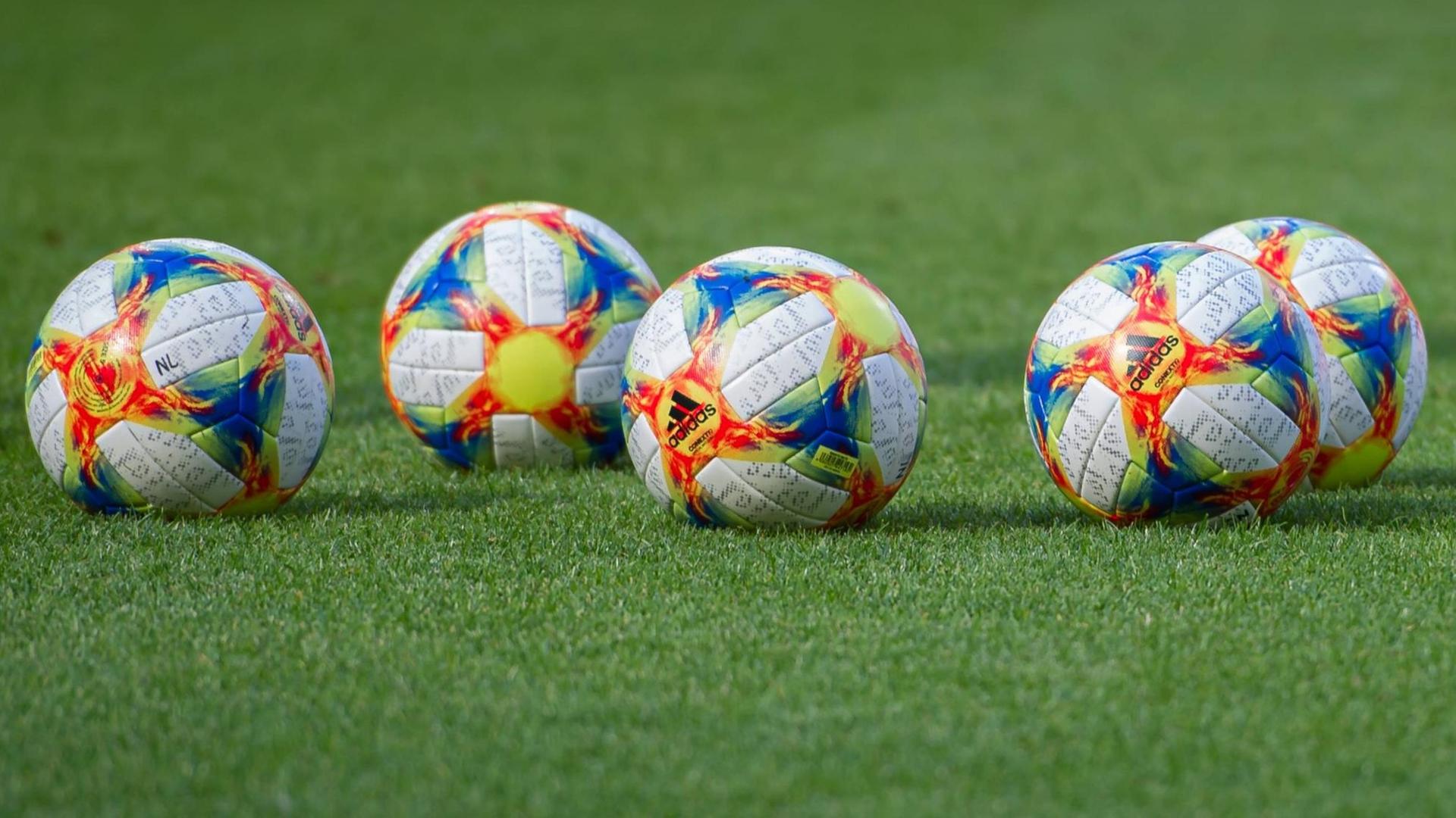 Fünf offizielle Spielbälle der Fußball-WM der Frauen 2019 liegen auf dem grünen Rasen. Fünf offizielle Spielbälle der Fußball-WM der Frauen 2019 liegen auf dem grünen Rasen.