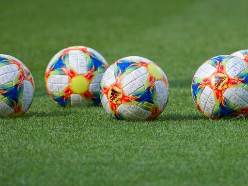 Fünf offizielle Spielbälle der Fußball-WM der Frauen 2019 liegen auf dem grünen Rasen.