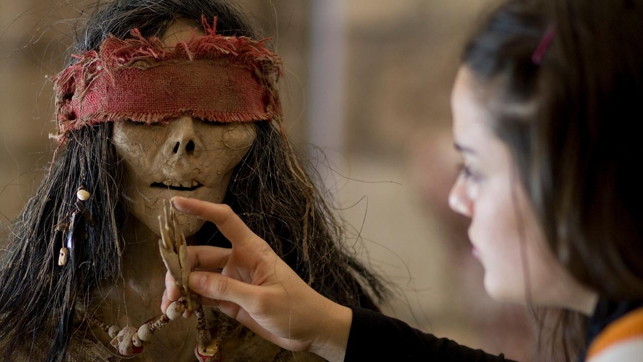 Filmausschnitt aus dem Film "La Flor". Eine zombiehafte Gestalt mit roter Augenbinde wird von einem Mädchen gefüttert Filmausschnitt aus dem Film "La Flor". Eine zombiehafte Gestalt mit roter Augenbinde wird von einem Mädchen gefüttert