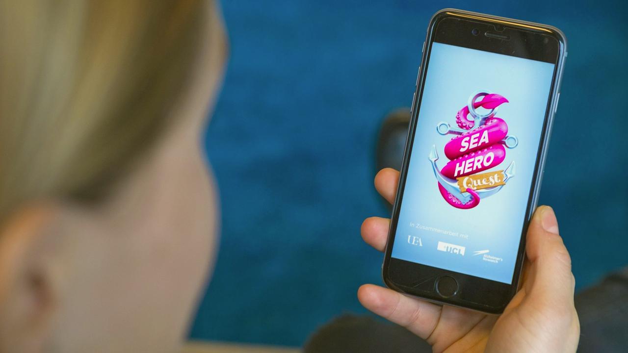 Ein Frau schaut sich auf ihrem Smartphone das Spiel Sea Hero Quest an. Ein Frau schaut sich auf ihrem Smartphone das Spiel Sea Hero Quest an.