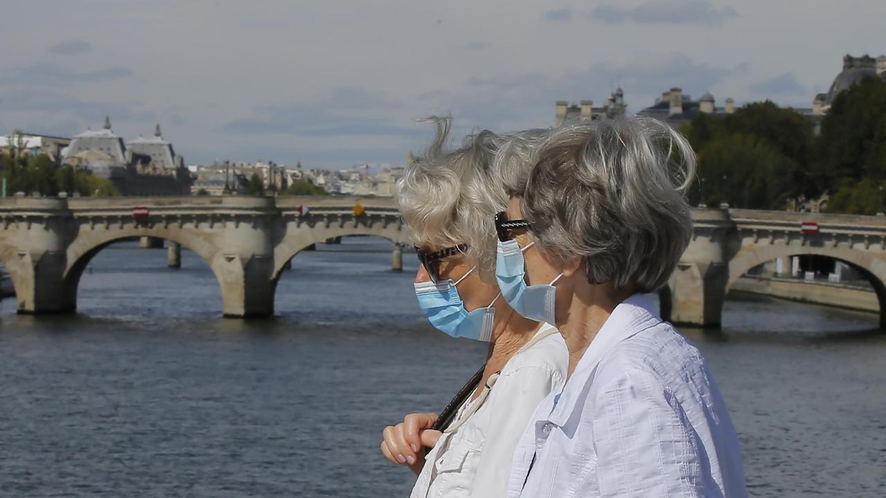 Zwei Passantinnen mit medizinischem Mundschutz spazieren über eine Brücke über die Seine. Zwei Passantinnen mit medizinischem Mundschutz spazieren über eine Brücke über die Seine.