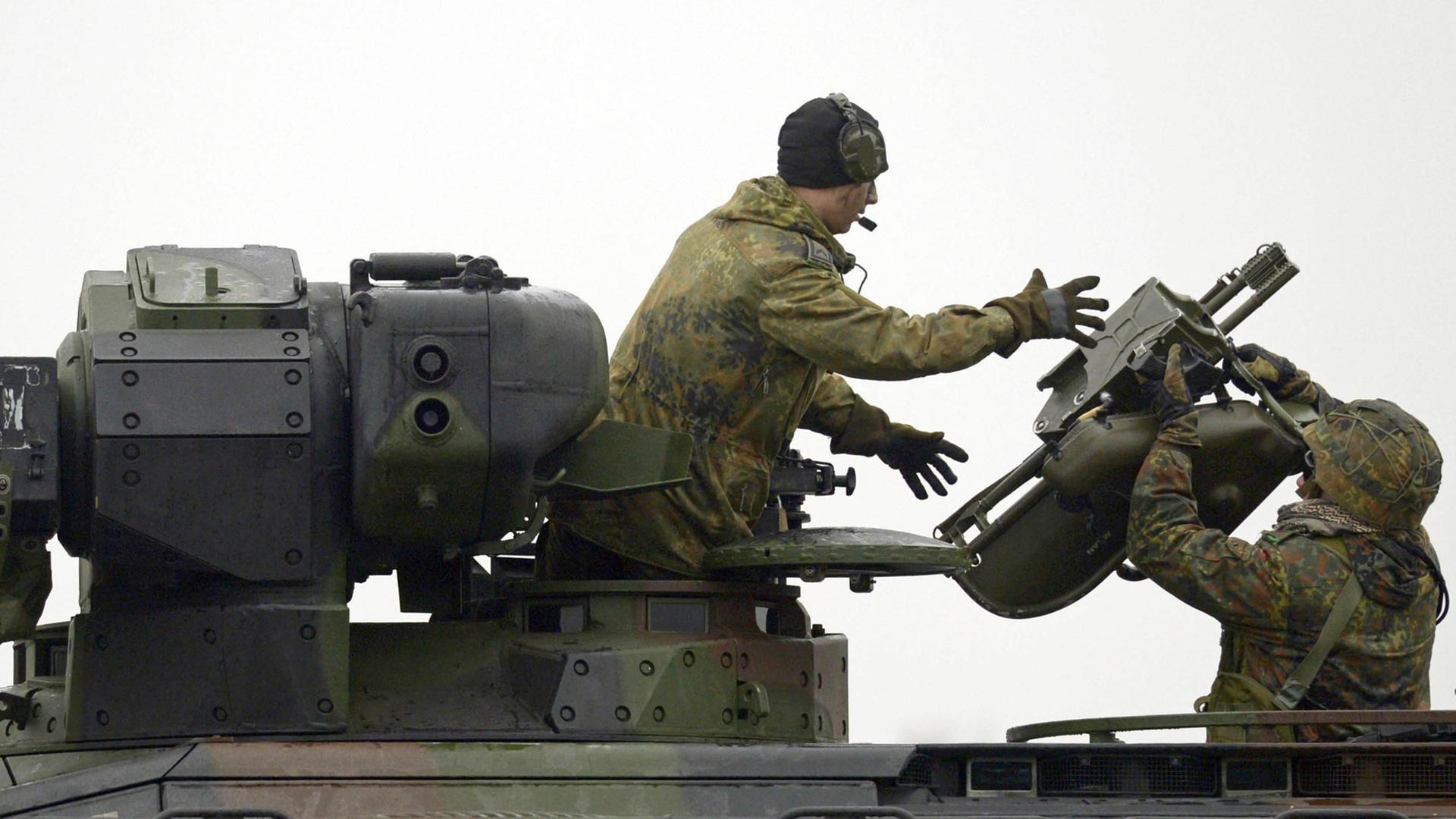 Ein Panzergrenadier reicht dem Kommandanten eines Schützenpanzer vom Typ "Marder" eine Startvorrichtung für eine Panzerabwehrwaffe vom Typ "Milan".