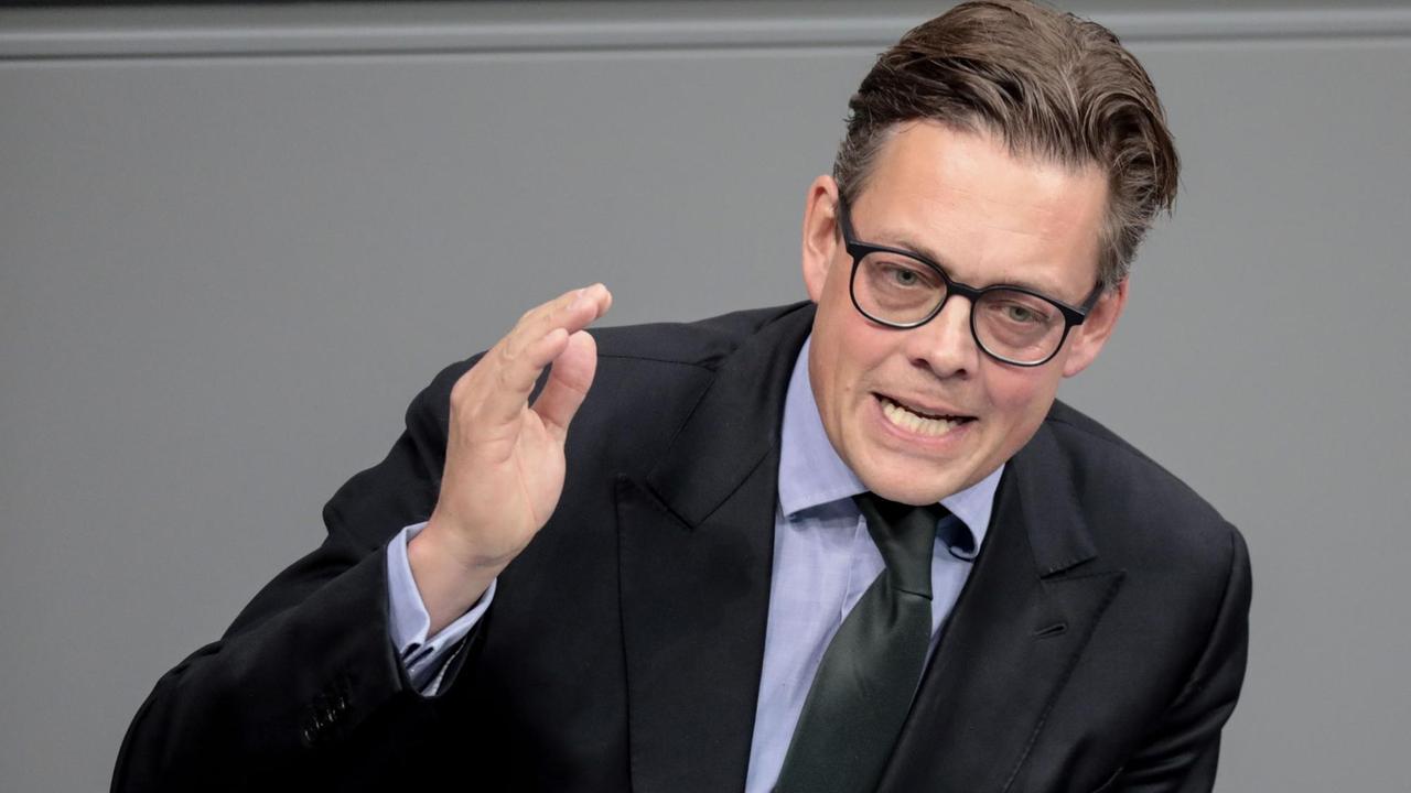 Der Grünen-Politiker Konstantin von Notz steht im Bundestag in einem schwarzen Anzug und einem grauen Hemd hinter einem Rednerpult und gestikuliert mit der rechten Hand. Der Grünen-Politiker Konstantin von Notz steht im Bundestag in einem schwarzen Anzug und einem grauen Hemd hinter einem Rednerpult und gestikuliert mit der rechten Hand.