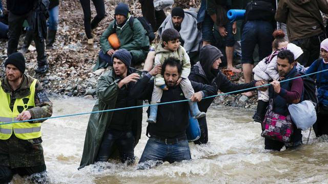 Flüchtlinge aus Idomeni durchqueren einen Grenzfluss Richtung Mazedonien