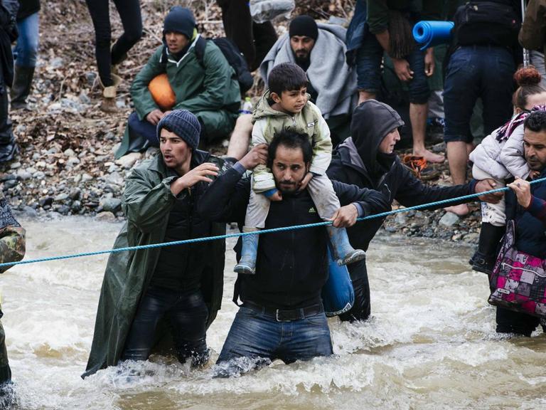 Flüchtlinge aus Idomeni durchqueren einen Grenzfluss Richtung Mazedonien