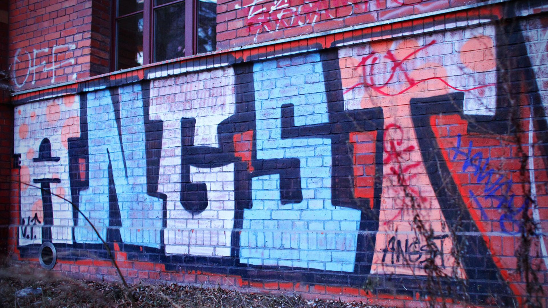 Ein Graffiti mit dem Wort "Angst" auf einer Backsteinwand eines Hauses Ein Graffiti mit dem Wort "Angst" auf einer Backsteinwand eines Hauses