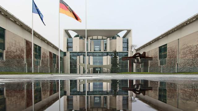 Das Bundeskanzleramt spiegelt sich in einer Wasserpfütze an einem tristen und schmuddeligen Regentag in Berlin.