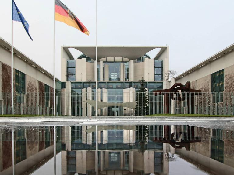 Das Bundeskanzleramt spiegelt sich in einer Wasserpfütze an einem tristen und schmuddeligen Regentag in Berlin.
