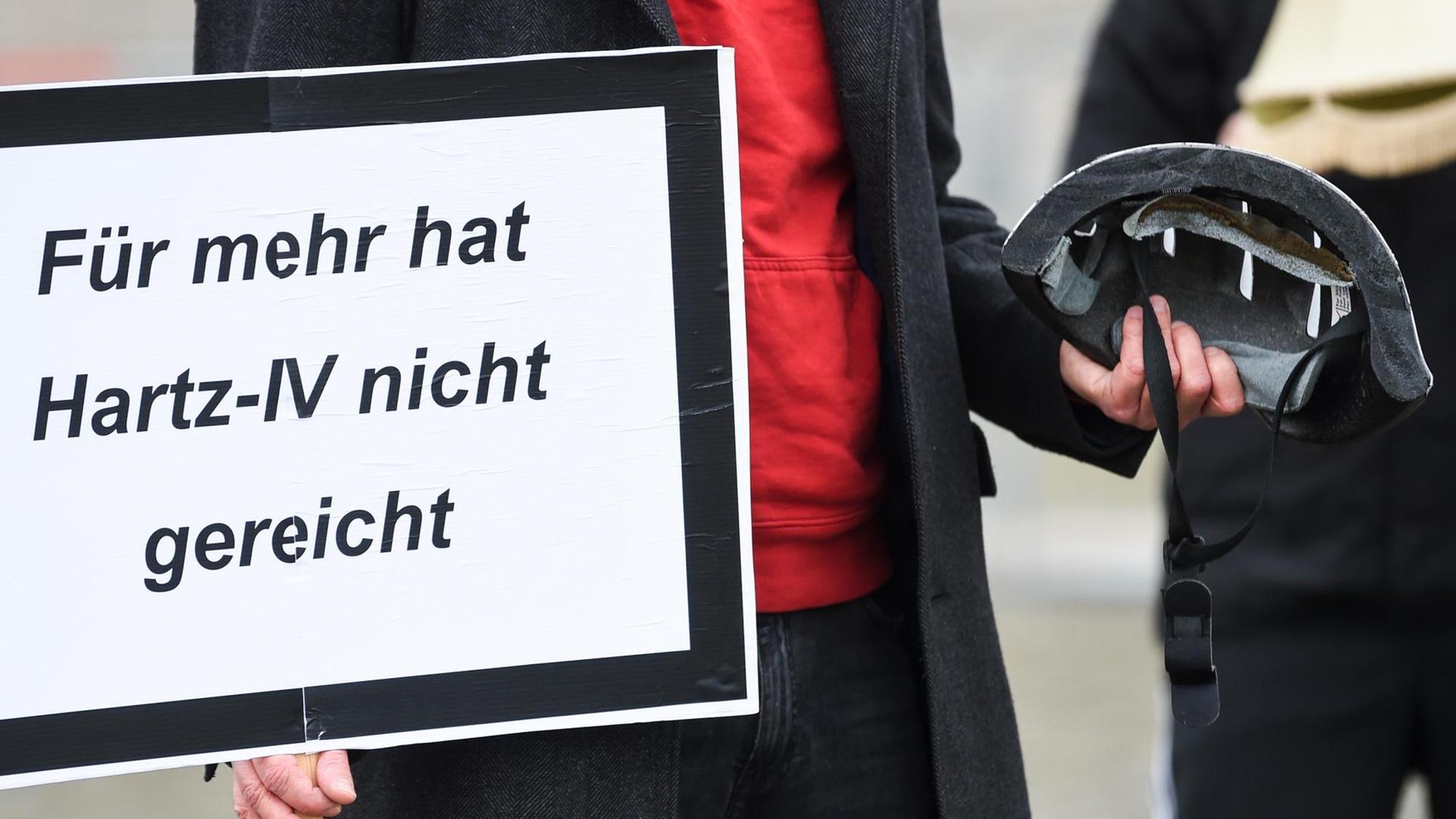 Ein Demonstrant hält ein Schild mit der Aufschrift "Für mehr hat Hartz-IV nicht gereicht" und einen halben Fahrradhelm in der Hand. Vor dem Deutschen Bundestag demonstrieren Personen der Aktion «Keine halben Sachen: Corona-Hilfen für die Ärmsten» für mehr Corona-Hilfen.