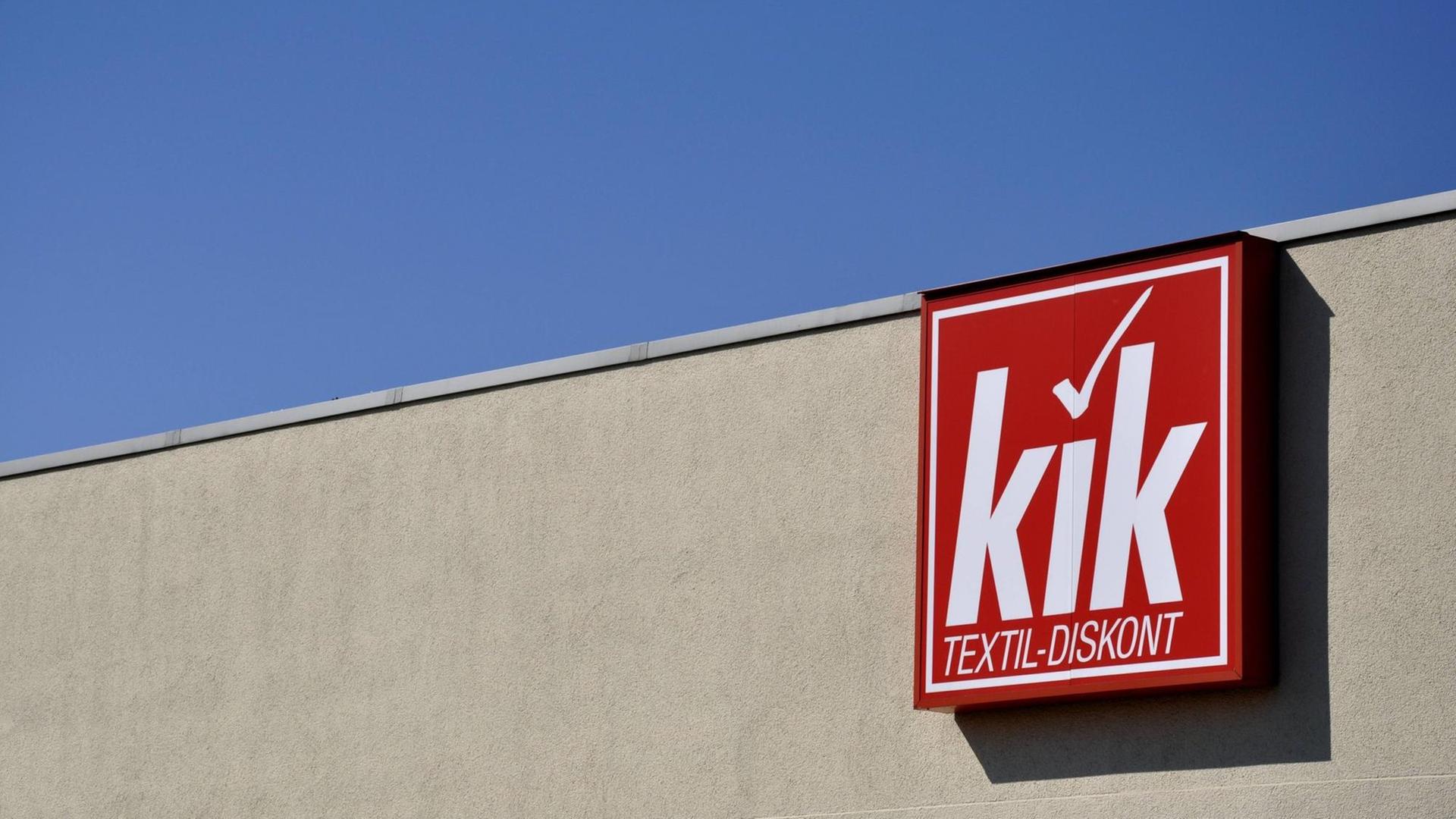 Schild von Kik an einem grauen Gebäude vor blauem Himmel Schild von Kik an einem grauen Gebäude vor blauem Himmel