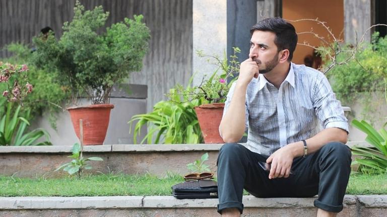 Der Designer Wajahat Rather sitzt vor einem Haus.