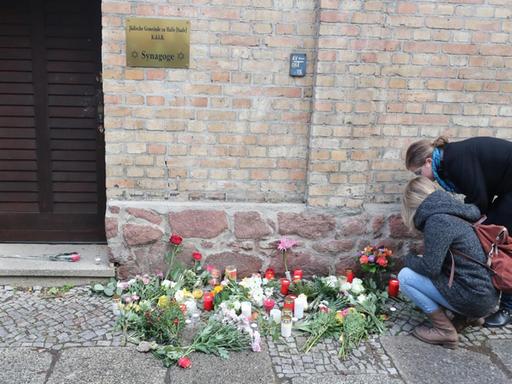 Menschen legen Blumen vor der Synagoge in Halle ab