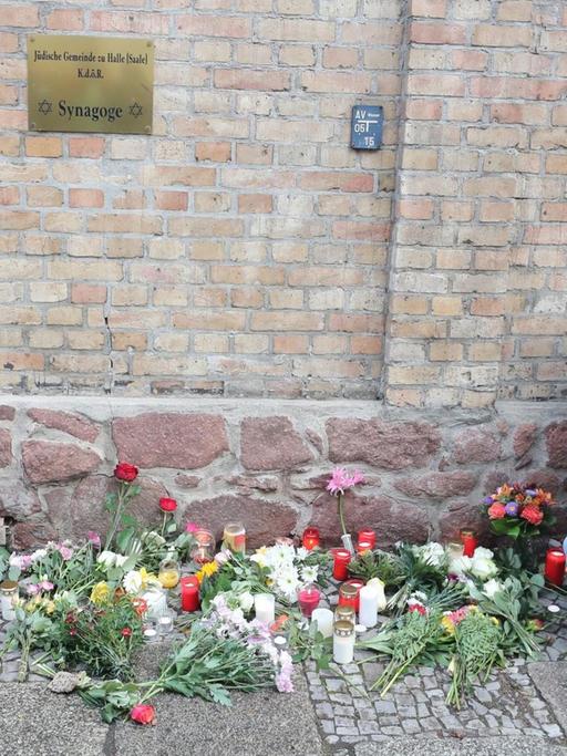 Menschen legen Blumen vor der Synagoge in Halle ab.