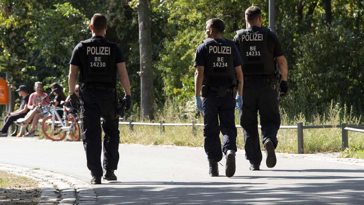 Drei Polizeibeamte laufen durch den Görlitzer Park. Drei Polizeibeamte laufen durch den Görlitzer Park.