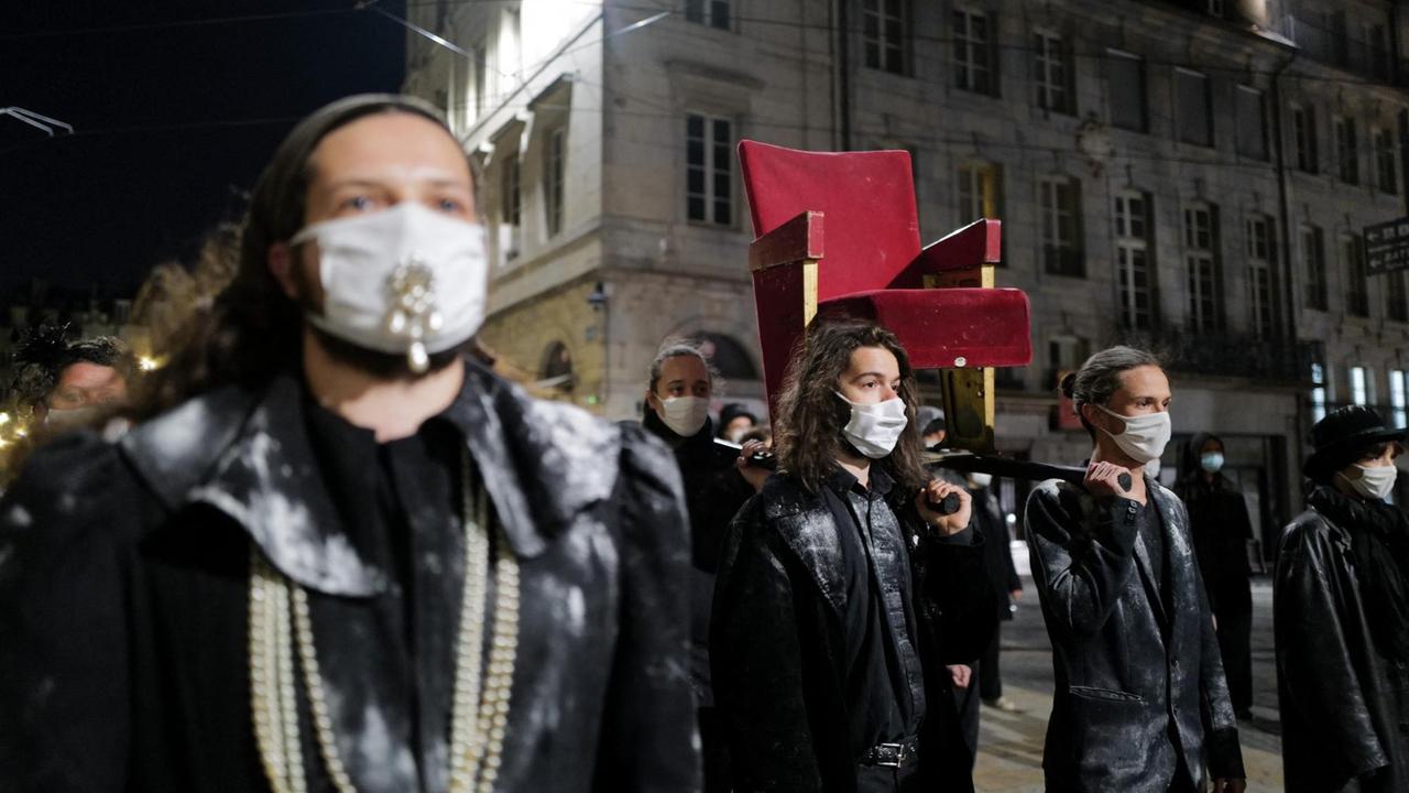 Demonstrierende tragen einen rot bezogenen Theatersessel durch die Straßen Demonstrierende tragen einen rot bezogenen Theatersessel durch die Straßen