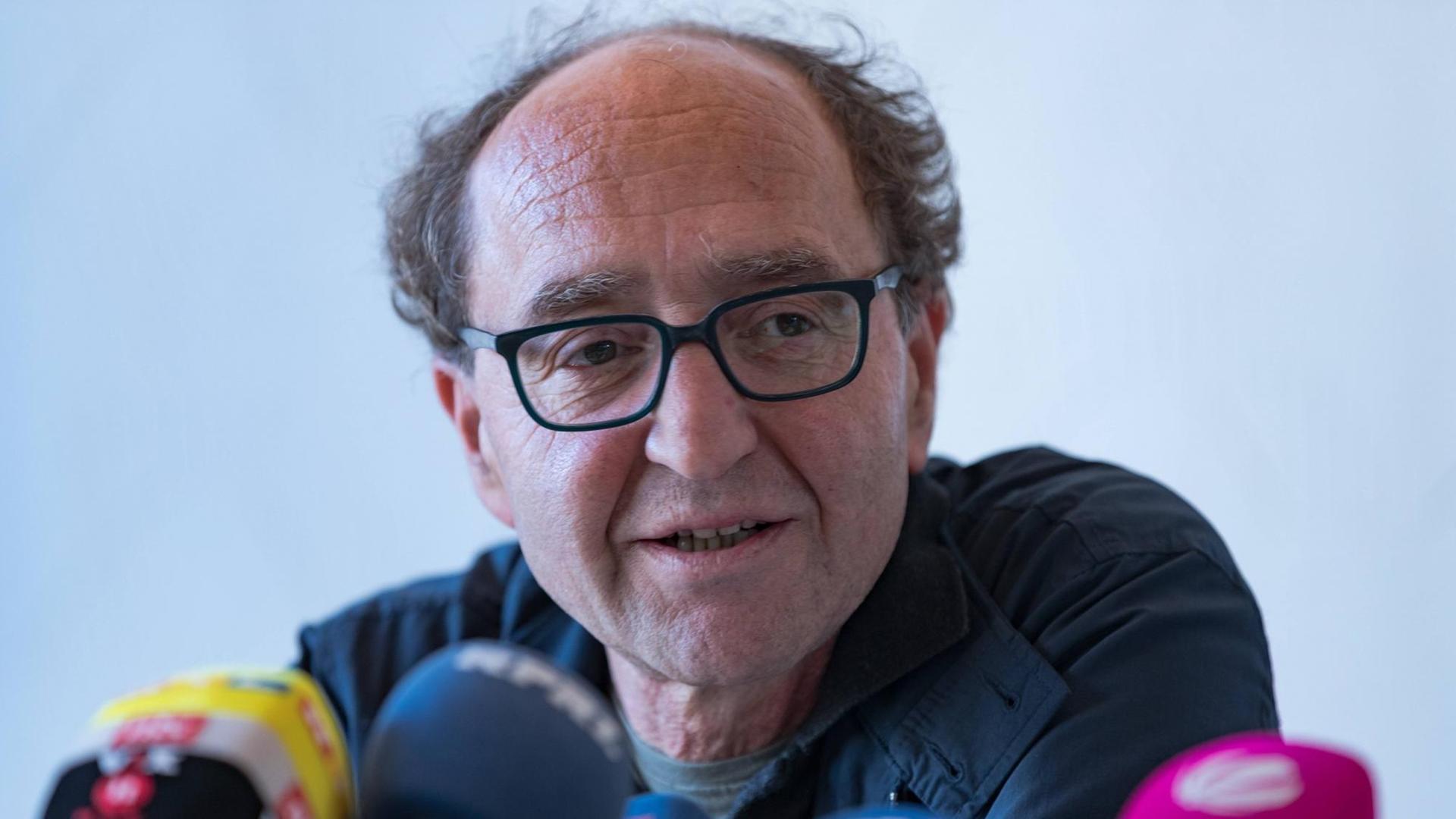 Dogan Akhanli sitzt hinter einer Reihe von Mikrofonen. Dogan Akhanli sitzt hinter einer Reihe von Mikrofonen.