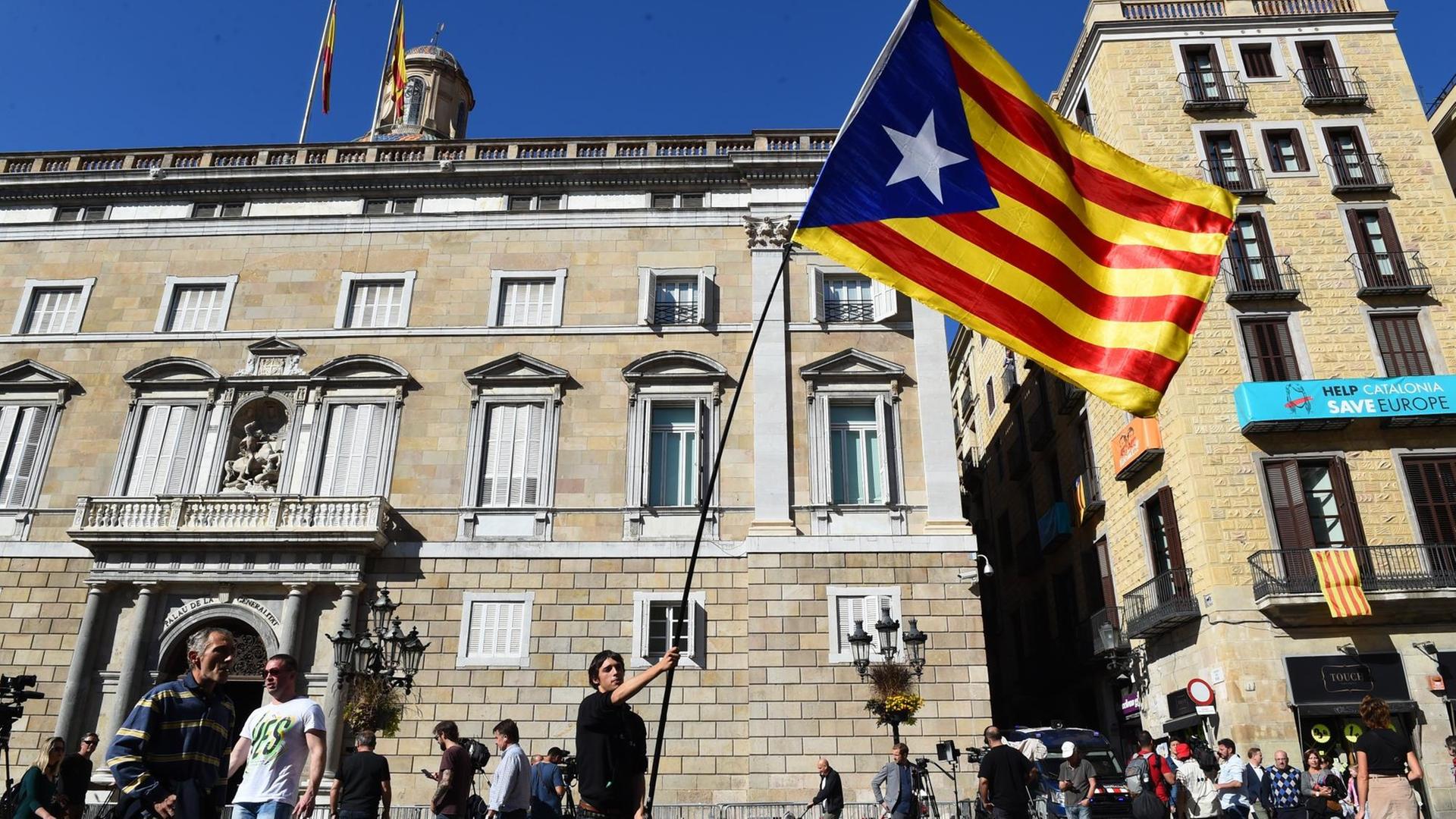Der Student Joan Correa schwenkt am 30.10.2017 die Flagge Kataloniens vor dem Gebäude der Provinzregierung in Barcelona, um den abgesetzten Lokalpräsidenten Carles Puigdemont zu unterstützen. Der Student Joan Correa schwenkt am 30.10.2017 die Flagge Kataloniens vor dem Gebäude der Provinzregierung in Barcelona, um den abgesetzten Lokalpräsidenten Carles Puigdemont zu unterstützen.