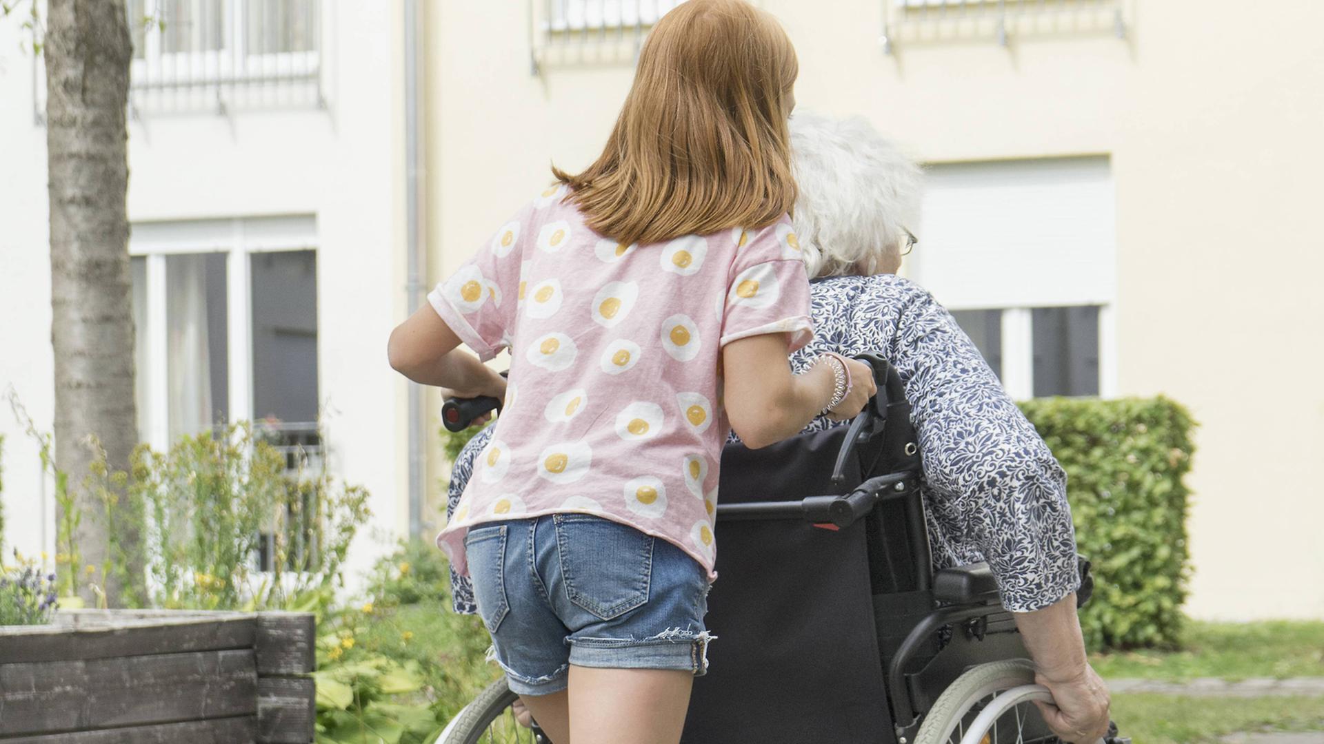 Ein junges Mädchen schiebt den Rollstuhl einer erwachsenen Frau. Ein junges Mädchen schiebt den Rollstuhl einer erwachsenen Frau.