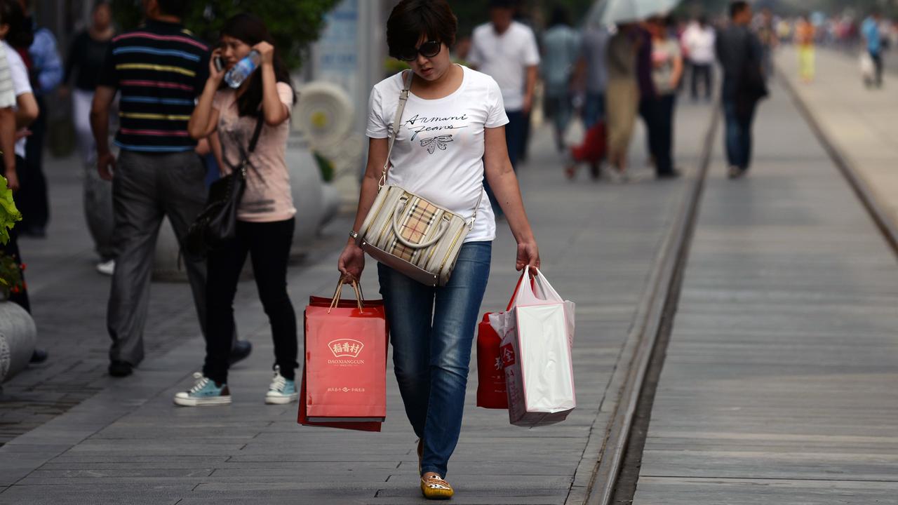 Eine Frau mit Einkaufstüten in einer Einkaufsstraße in Peking. Eine Frau mit Einkaufstüten in einer Einkaufsstraße in Peking.