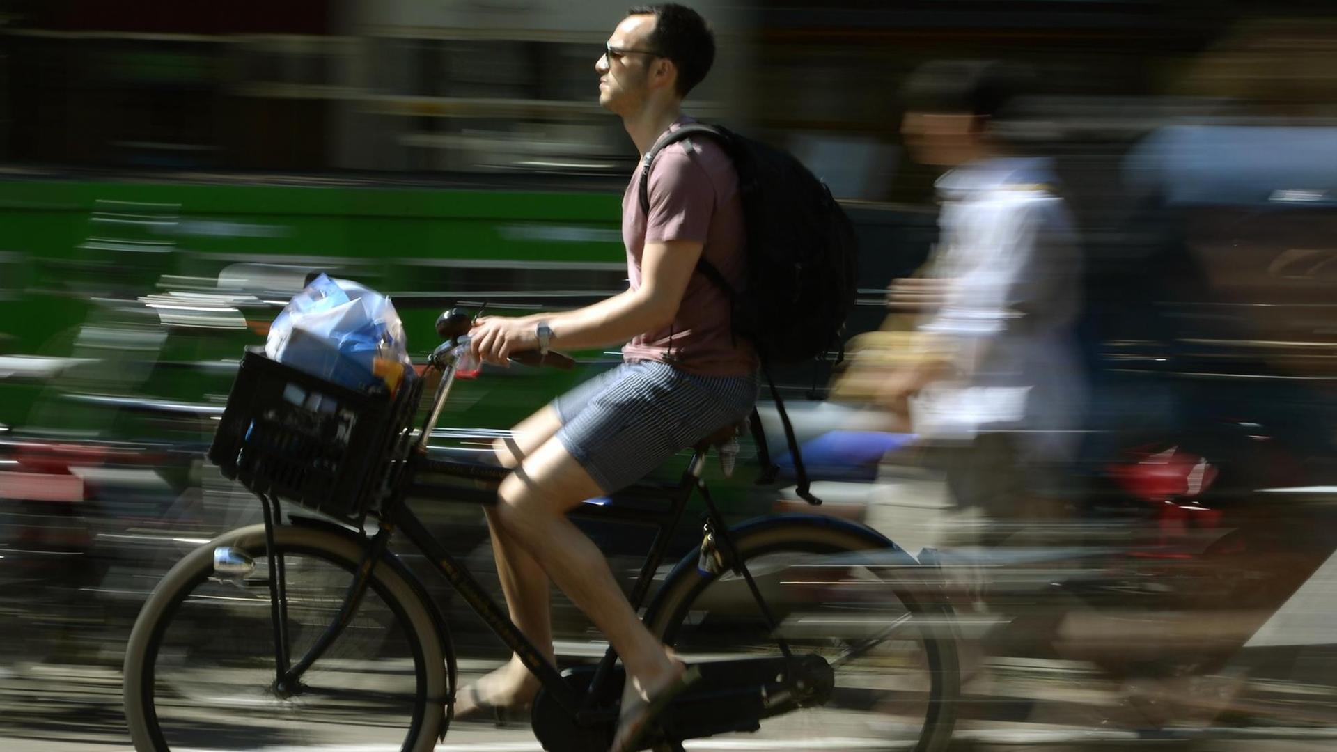 Ein Mann transport in seinem Fahrradkorb vorne am Lenker seine Einkäufe, während entlang einer der Amsterdamer Grachten fährt. Ein Mann transport in seinem Fahrradkorb vorne am Lenker seine Einkäufe, während entlang einer der Amsterdamer Grachten fährt.