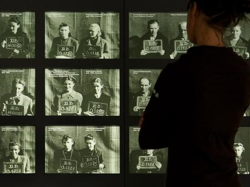Eine Besucherin betrachtet in der Gedenkstätte Bergen-Belsen Registrierungsfotos polnischer Kriegsgefangener aus dem Warschauer Aufstand.
