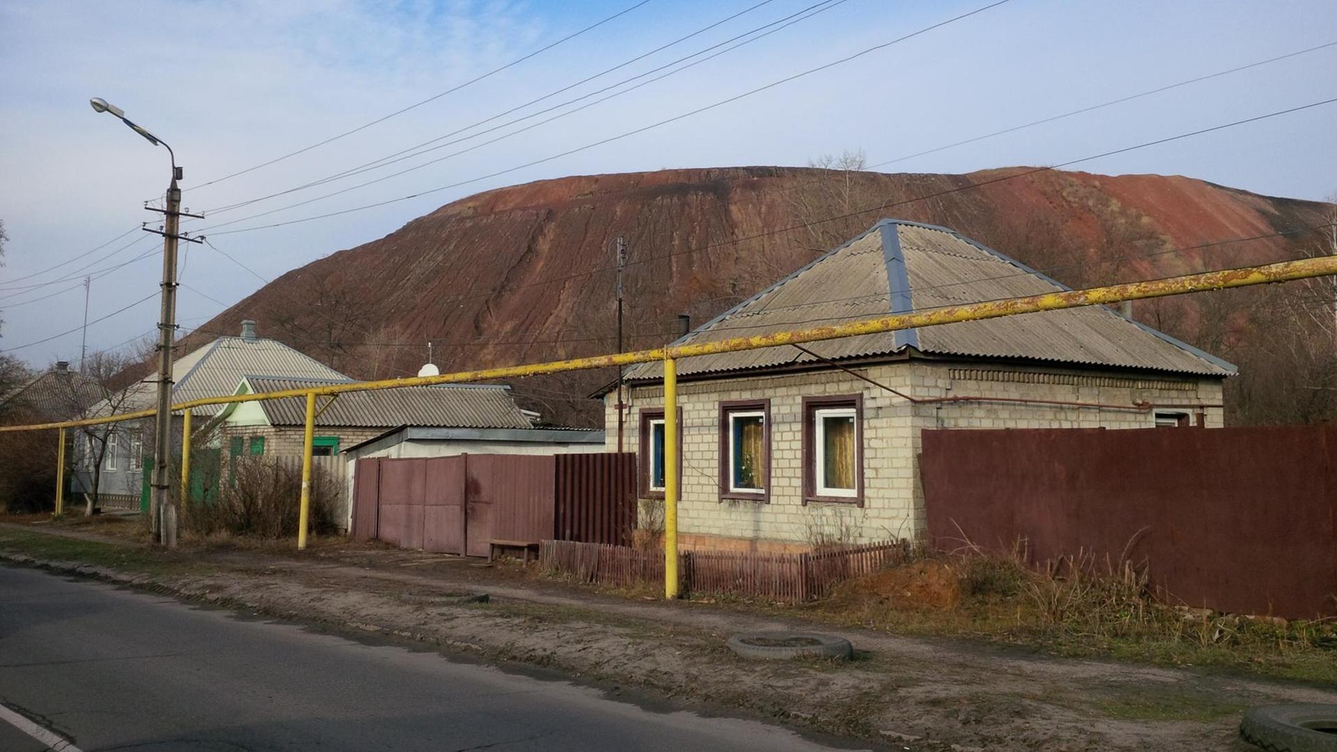 Mehrere Häuser stehen vor einem Berg an einer Straße. Mehrere Häuser stehen vor einem Berg an einer Straße.