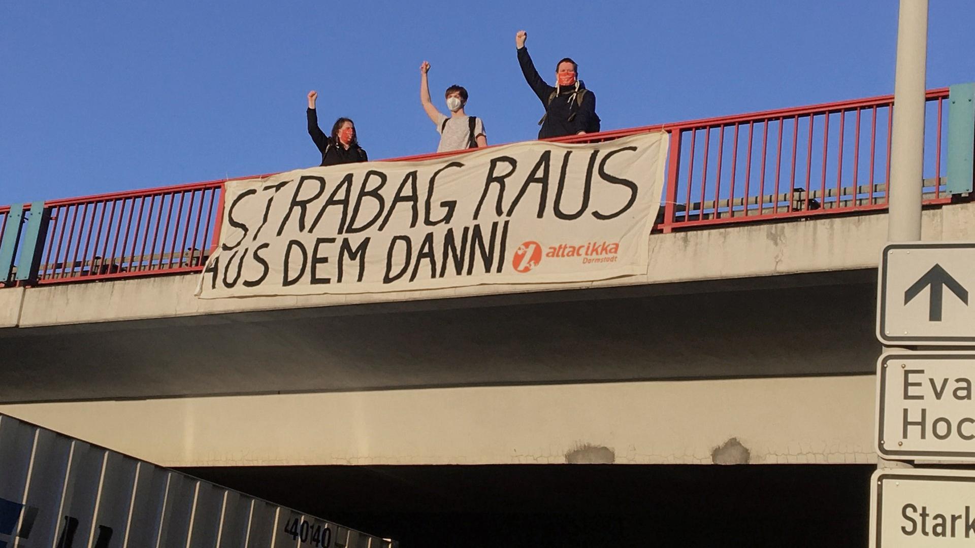 Auf einer Autobahnbrücke posieren drei Aktivisten vor einem Stofftransparent mit der Aufschrift "Strabag raus aus dem Danni" Auf einer Autobahnbrücke posieren drei Aktivisten vor einem Stofftransparent mit der Aufschrift "Strabag raus aus dem Danni"
