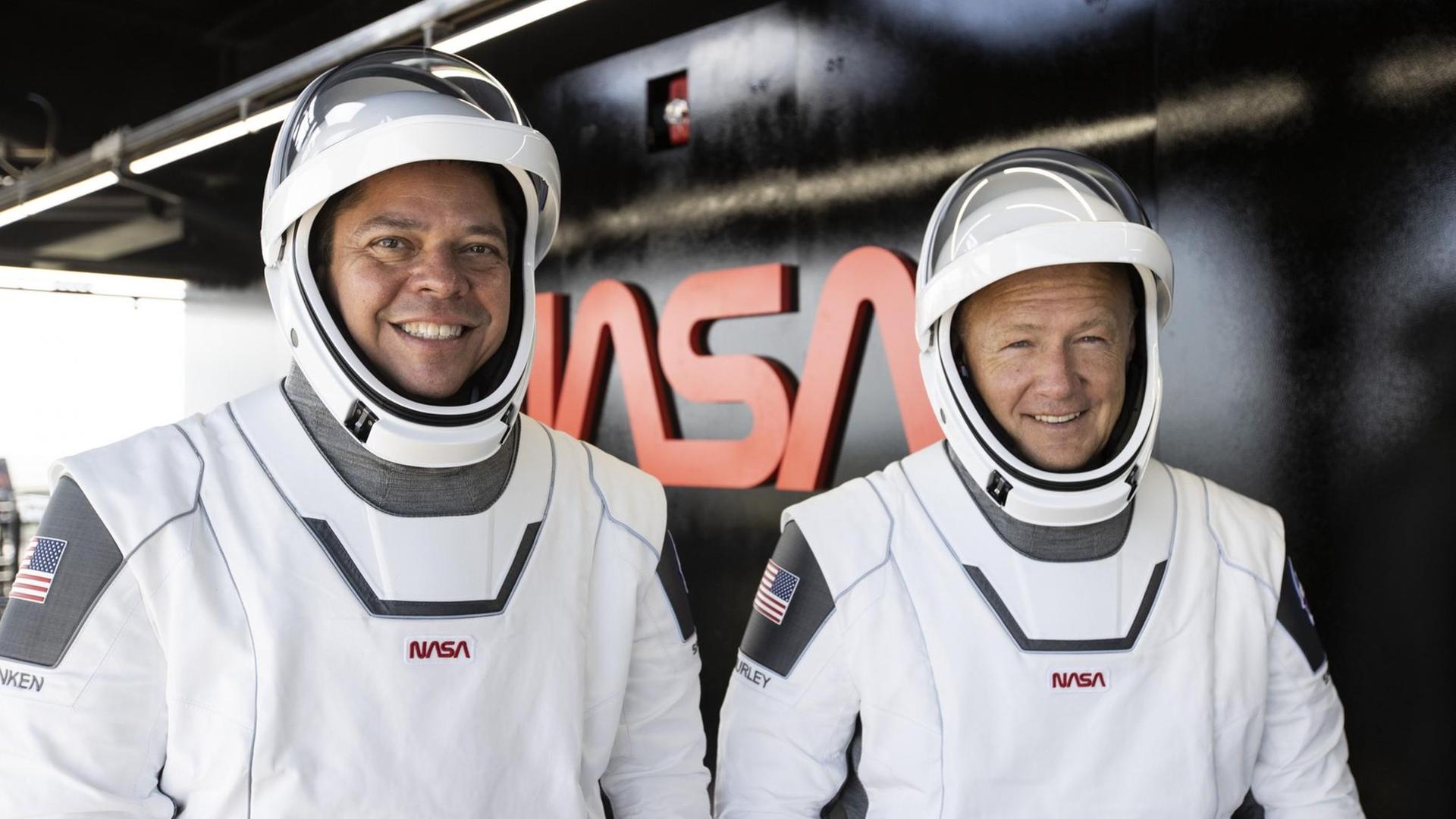 Die beiden Astronauten Bob Behnken und Doug Hurley in weißen Raum-Anzügen. Die beiden Astronauten Bob Behnken und Doug Hurley in weißen Raum-Anzügen.