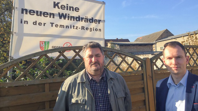 Thomas Voigt (li), der Bürgermeister von Temnitztal, und sein Stellvertreter Michael Mann (re) stehen vor einem Plakat, auf dem steht "Keine neuen Windräder in der Temnitz-Region". Thomas Voigt (li), der Bürgermeister von Temnitztal, und sein Stellvertreter Michael Mann (re) stehen vor einem Plakat, auf dem steht "Keine neuen Windräder in der Temnitz-Region".
