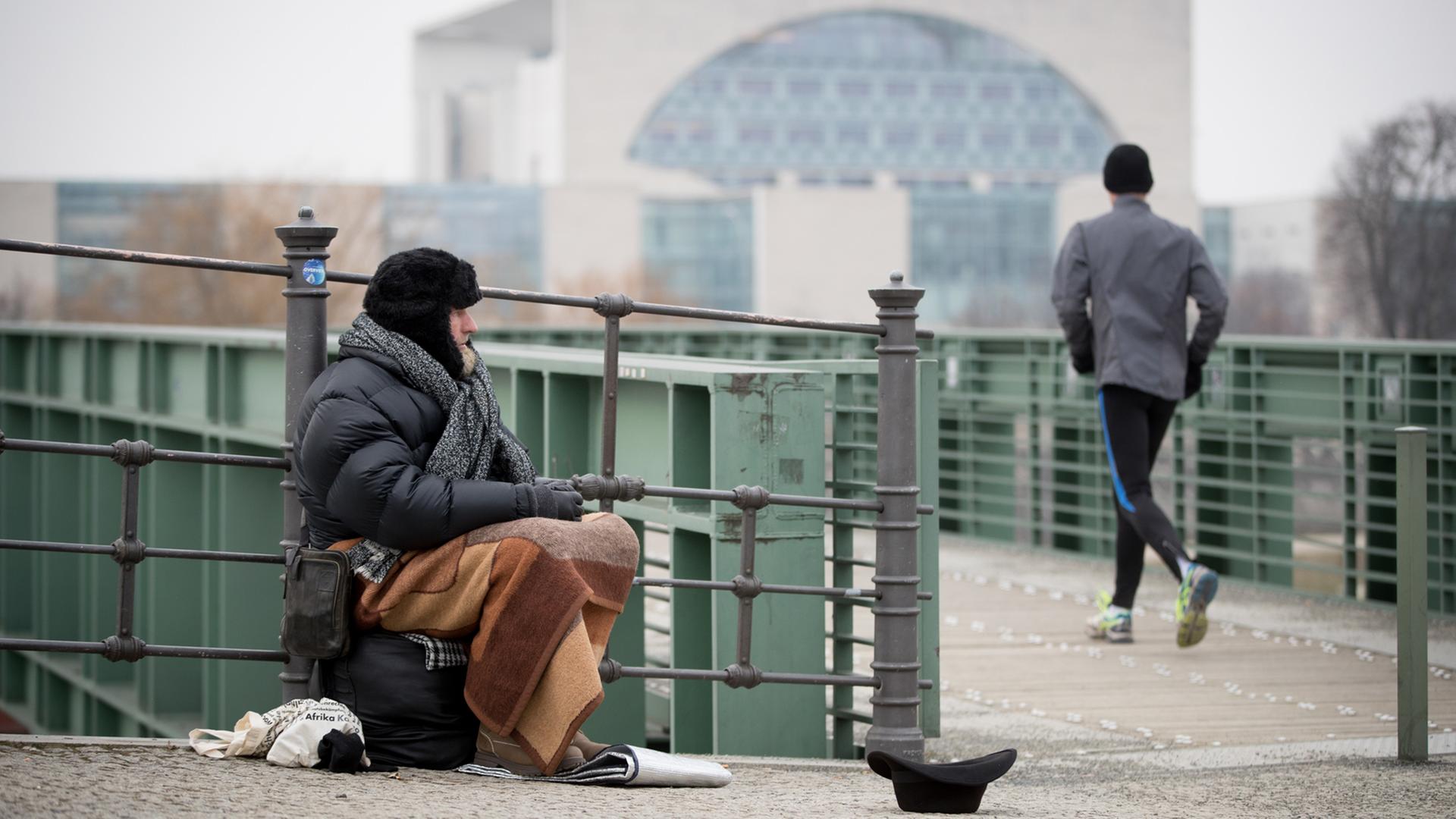 Ein Obdachloser sitzt in Berlin an der Spree im Regierungsviertel und bittet um Unterstützung Ein Obdachloser sitzt in Berlin an der Spree im Regierungsviertel und bittet um Unterstützung