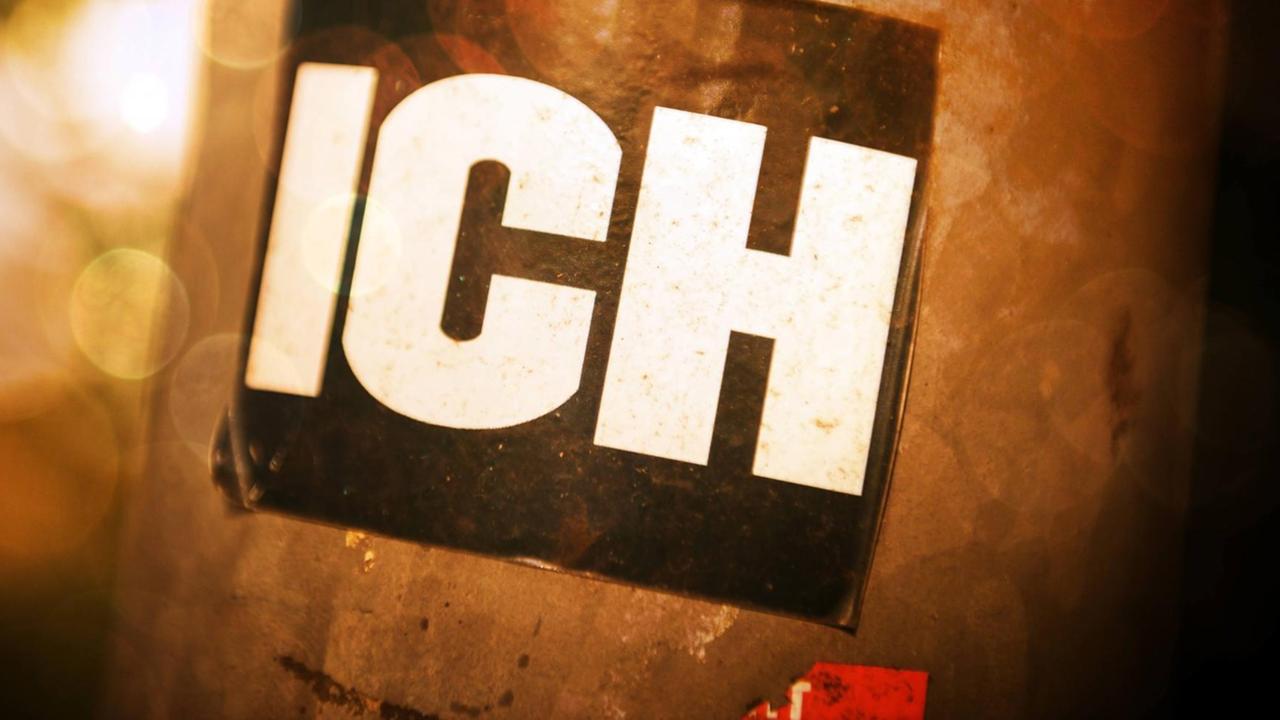 An einem Laternenpfahl klebt ein Aufkleber mit dem Wort "Ich". An einem Laternenpfahl klebt ein Aufkleber mit dem Wort "Ich".
