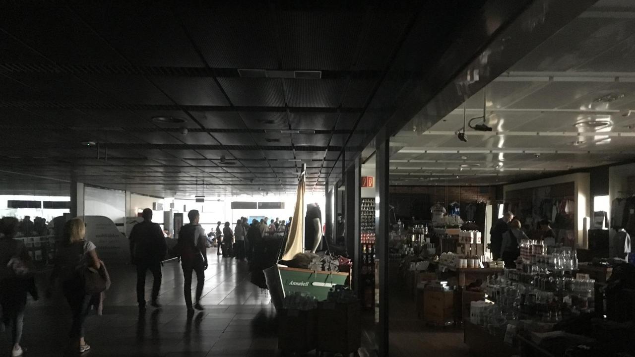 03.06.2018, Hamburg: Reisende gehen während eines Stromausfalls durch den unbeleuchteten Flughafen. 