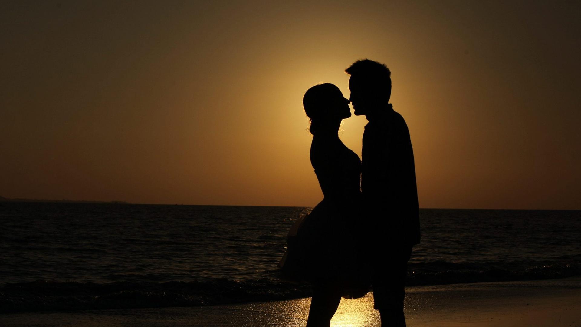 Paar im Sonnenuntergang am Strand (dpa / picture alliance / Zhang Jie)