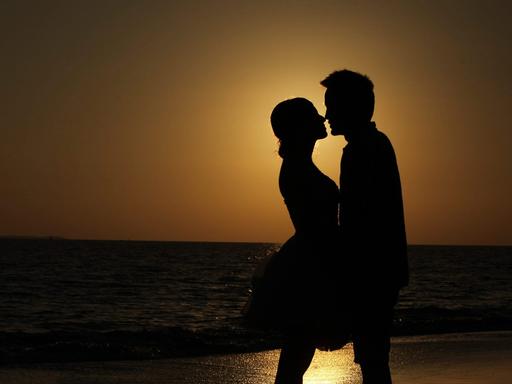 Paar im Sonnenuntergang am Strand (dpa / picture alliance / Zhang Jie)