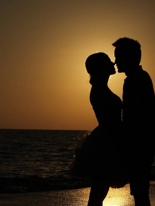 Paar im Sonnenuntergang am Strand (dpa / picture alliance / Zhang Jie)